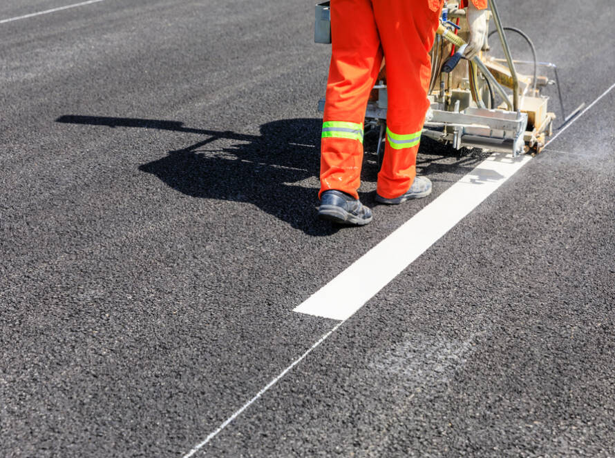 Road workers use hot-melt scribing machines to paint dividing lines